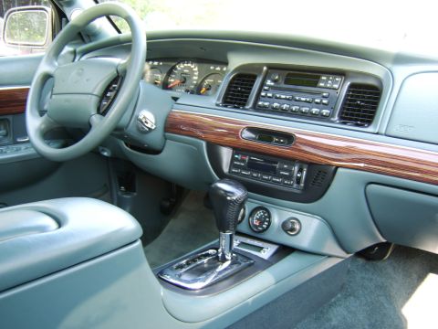 1996 Mercury Grand Marquis - The interior of a 1996 Mercury Grand Marquis features a wood-grain trim dashboard and a detailed center console with automatic transmission…