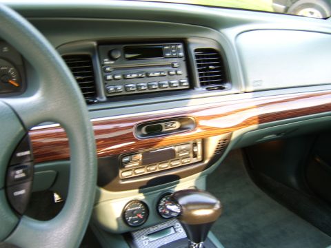 1996 Mercury Grand Marquis - The interior of a car shows a wood-trimmed dashboard with aftermarket gauges and a gear shifter.