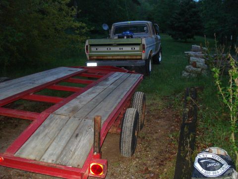 1967 Ford F-250 - A Ford pickup truck is seen from the rear, attached to a red trailer with wooden planks.