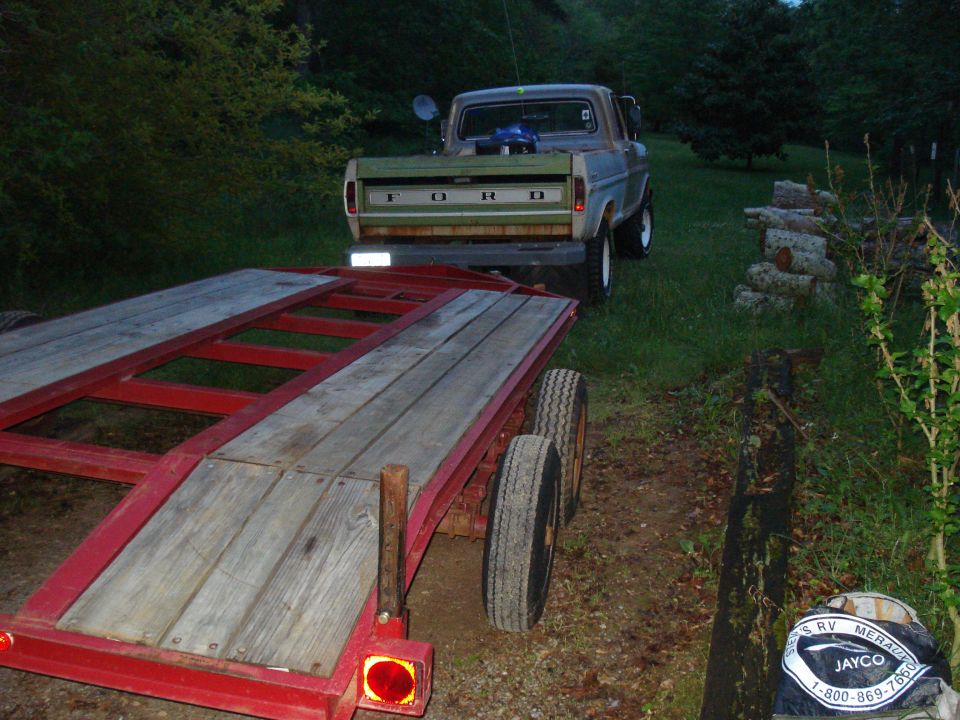 Ford pickup truck with a trailer hitched to it, parked on a grassy area