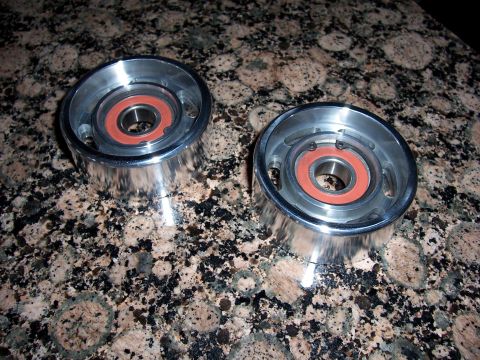 2002 Ford Mustang - Two chrome pulleys with orange seals are shown on a speckled granite surface.