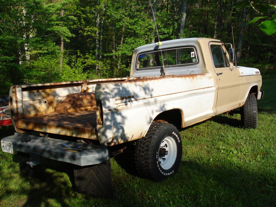 Tan and white 1967 Ford F-250 pickup truck, rear 3/4 view, parked on grass