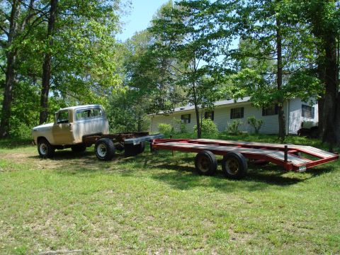1967 Ford F-250 - 1967 Ford F-250 chassis sits on a grassy lawn next to a red car hauler trailer.