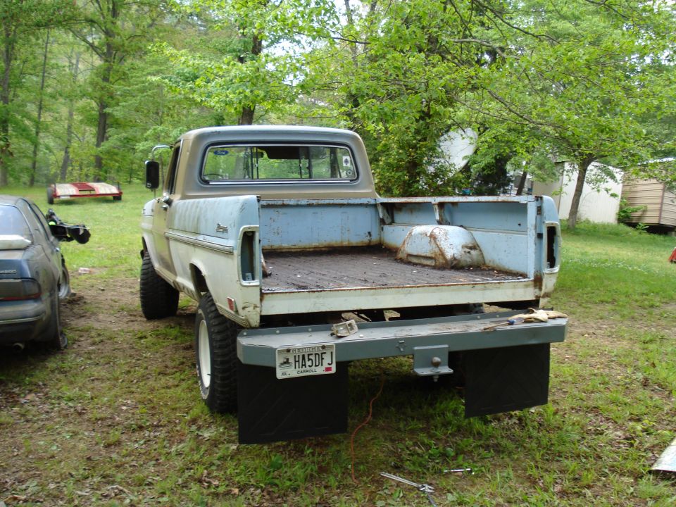 Rear view of a light blue and tan Ford F-Series pickup truck with a worn bed and mud flaps