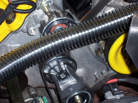 2002 Ford Mustang - Close-up view of engine components including a chrome ribbed hose and a yellow pulley.