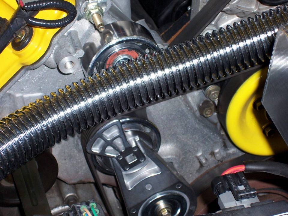 Engine bay with chrome ribbed hose, yellow pulley, and serpentine belt