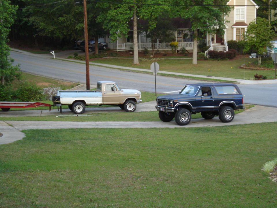 Ford F-150 pickup truck with a trailer, and a blue Ford Bronco parked on a driveway