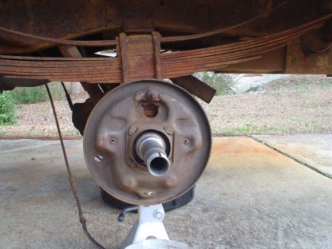 1967 Ford F-250 - Close-up of a vehicle's rear axle, drum brake, and leaf springs, undergoing maintenance.