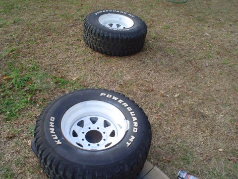 1967 Ford F-250 - Two off-road tires and white rims are visible on the grass. The tires are labeled "POWERGUARD MT" and "KUMHO".