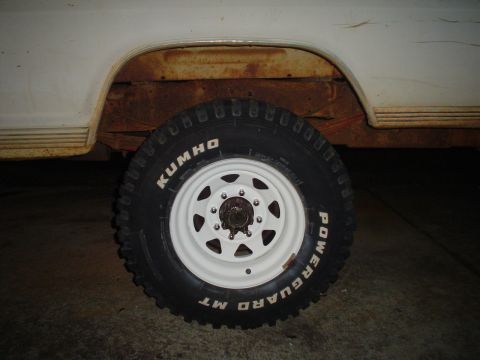 1967 Ford F-250 - Close-up of a tire and wheel assembly on a vehicle with visible rust on the fender.