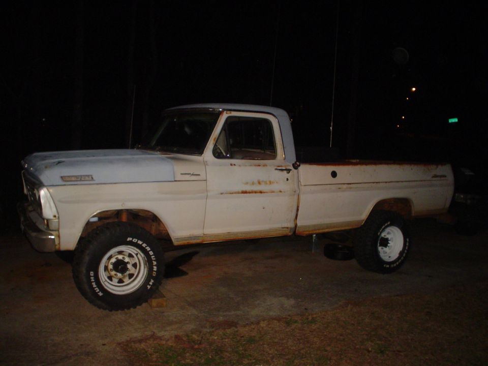 White Ford F-Series truck, side view, showing rust and wear. It has a light blue roof and hood