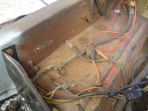1967 Ford F-250 - This photo shows a section of a vehicle's wiring harness, various colored wires and connectors on a rusty surface.