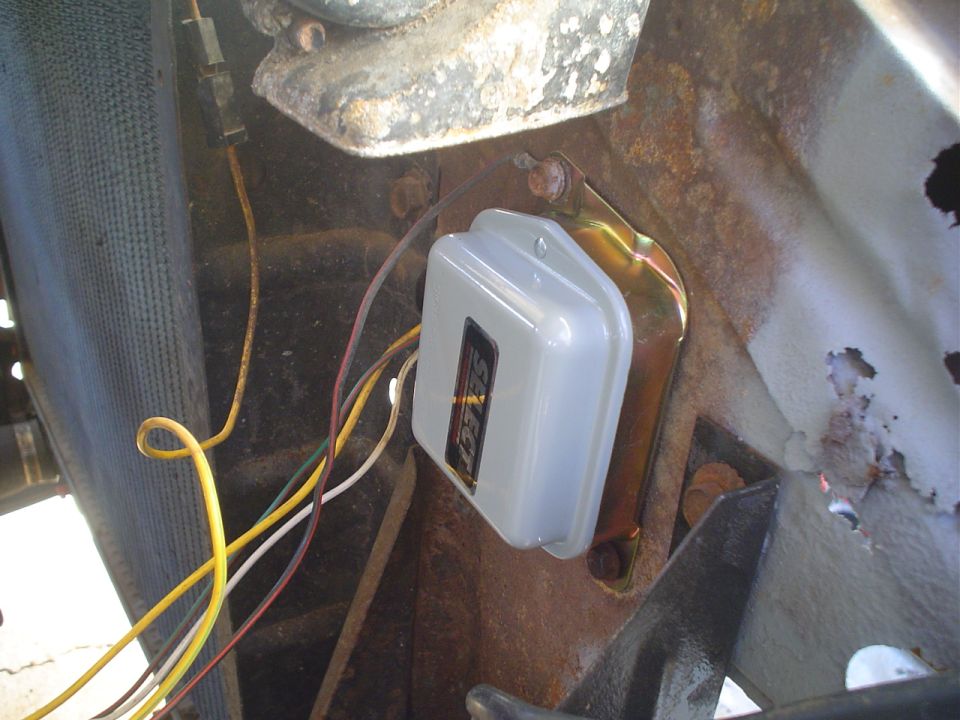 Gray electrical component with "SELECT" label, mounted on rusty metal bracket, with yellow and white wires