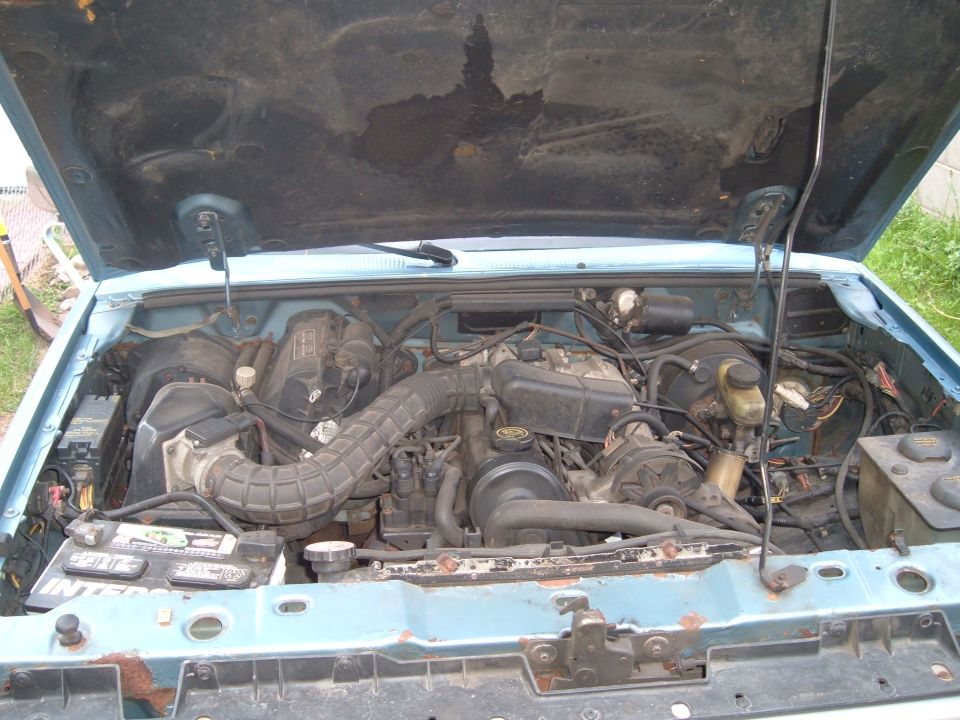 Engine bay of a light blue truck with hood open