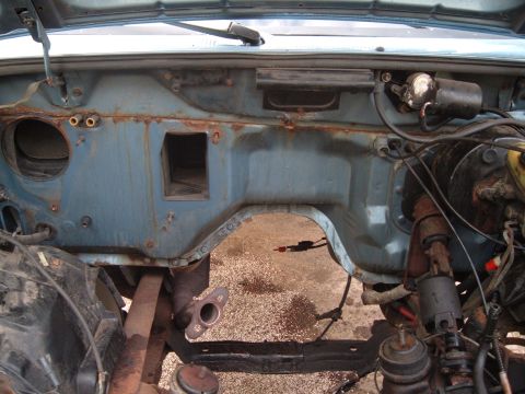 1990 Ford Ranger - The firewall of an engine bay shows significant rust and is missing many components.