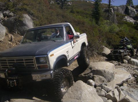 1986 Ford Bronco - Ford Bronco tackling a challenging off-road course with other vehicles present.
