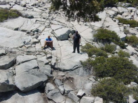 1986 Ford Bronco - Two men are in a rocky, mountainous area with scattered green bushes.