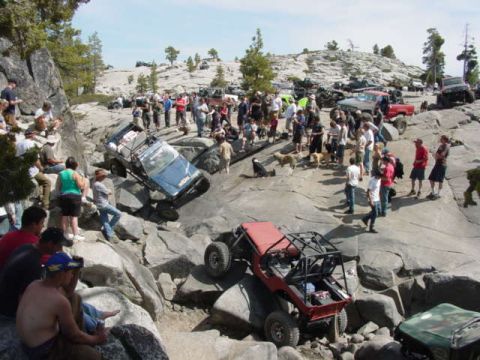 1986 Ford Bronco - Spectators watch as off-road vehicles tackle a challenging rocky course during an event.
