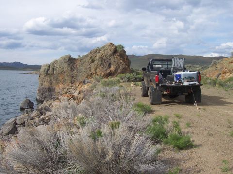 1994 Ford F-150 - A 1994 Ford F-150 is parked on a dirt road next to a rocky shoreline, with fishing equipment loaded in the truck bed.
