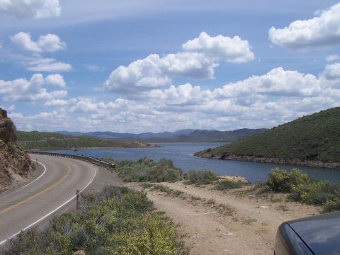 1994 Ford F-150 - A scenic view of a winding road next to a large body of water on a partly cloudy day.