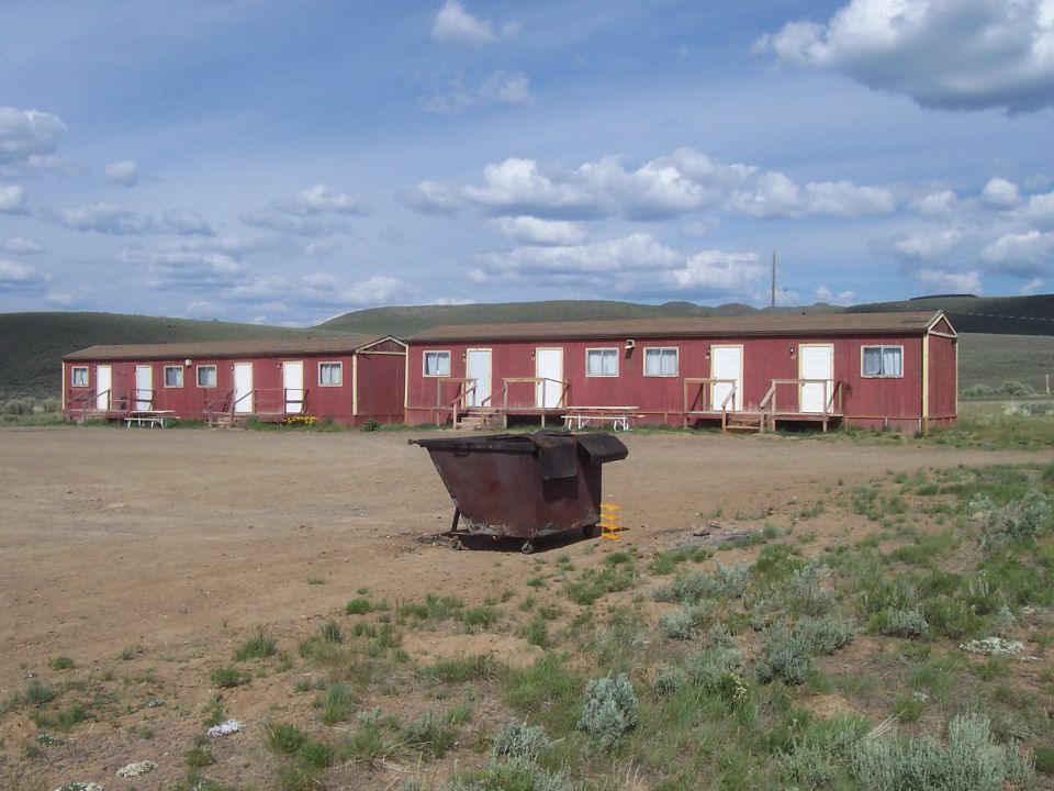 Dumpster in front of red buildings under a cloudy sky