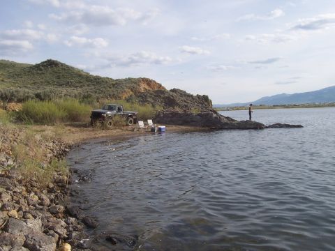 1994 Ford F-150 - A Ford F-150 is parked on the shore of a lake where a person is fishing.