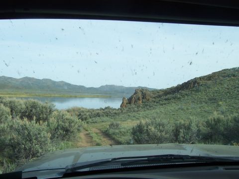1994 Ford F-150 - View from inside a vehicle driving on a dirt road towards a lake, with mountains in the background.