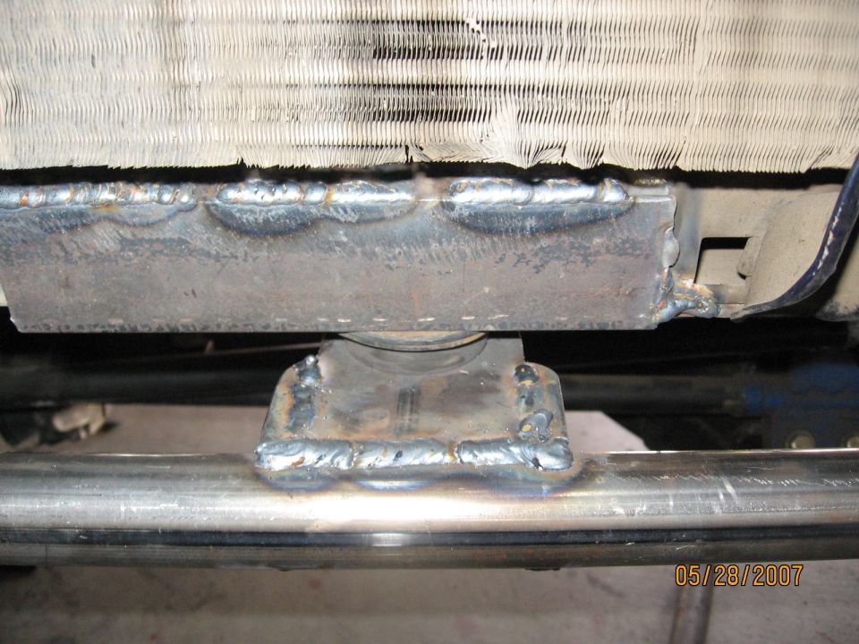 Welded steel mount securing a radiator core to a tube crossmember