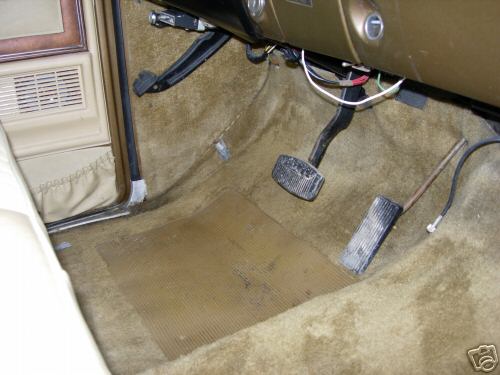 1979 Ford F-150 interior floor with tan carpet, rubber floor mat, and brake and accelerator pedals