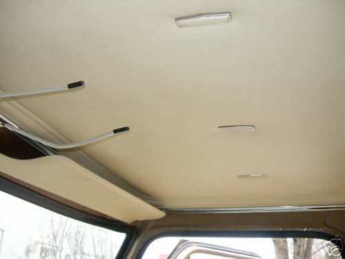 Interior ceiling of a vehicle with three dome lights and sun visors. Watermark reads SUPERMOTORS.NET