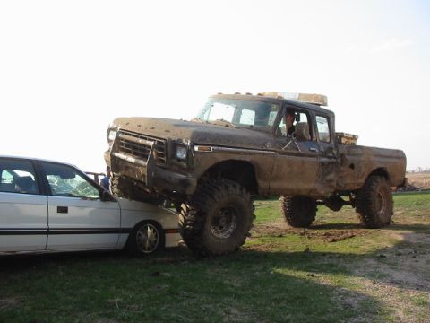 1979 Ford F-250 - A lifted 1979 Ford F-250 is shown on top of a sedan, covered in mud.