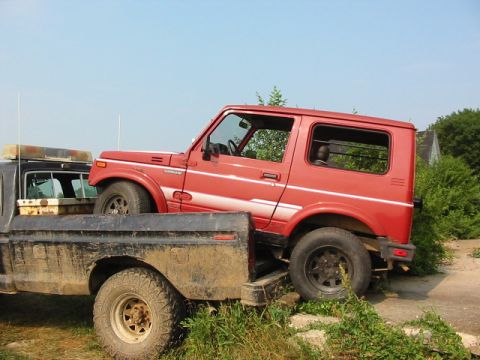 1979 Ford F-250 - A red Suzuki Samurai is being loaded into the bed of a flatbed truck.