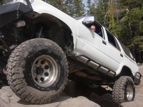 1985 Toyota Hilux - Modified white SUV navigating a rocky trail with a person inside.
