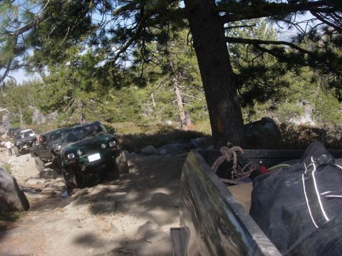 1985 Toyota Hilux - Several off-road vehicles, including a 1985 Toyota Hilux, travel on a challenging dirt path.
