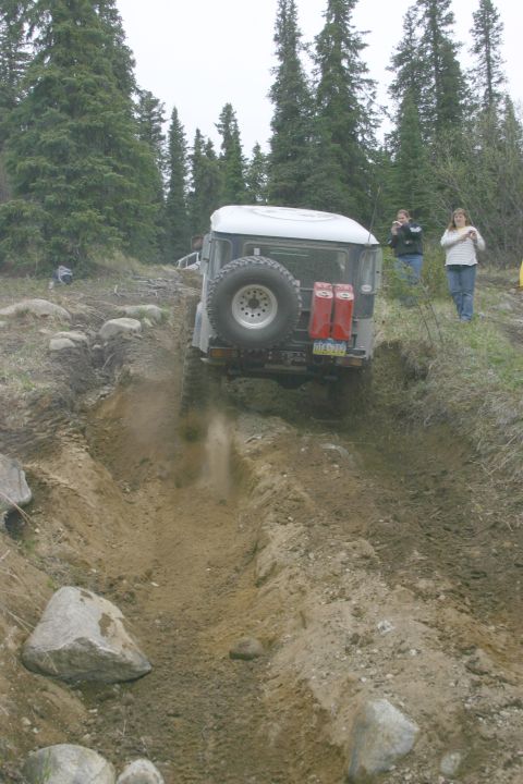 2003 Jeep TJ - Off-road vehicle navigates a challenging dirt path, with spectators observing the action.