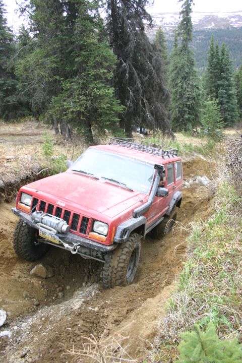 2003 Jeep TJ - Red Jeep Cherokee XJ navigates a challenging dirt trail with a winch and snorkel installed.