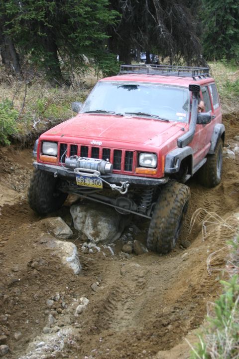 2003 Jeep TJ - A red Jeep Cherokee XJ navigates a rocky, off-road trail with a winch and snorkel attached.