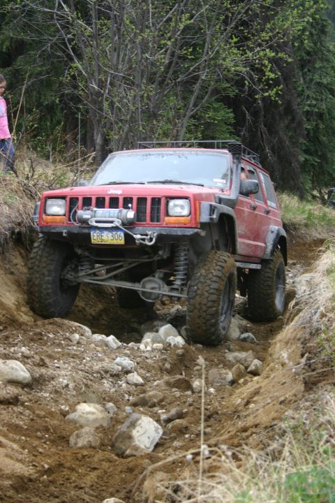 2003 Jeep TJ - A red Jeep Cherokee XJ navigates a rocky, off-road trail.
