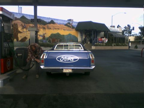 1972 Ford Ranchero - A blue 1972 Ford Ranchero is seen from the rear at a gas station with a mural in the background.
