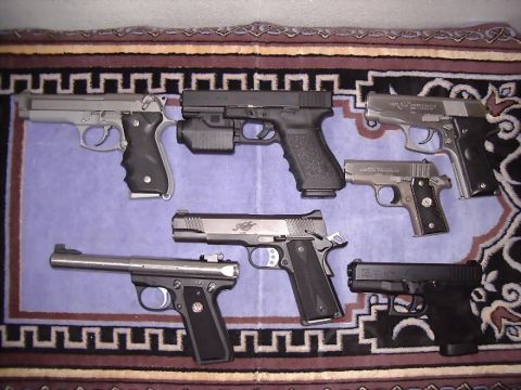1985 Ford Bronco - A variety of handguns are displayed on a rug, with a watermark at the bottom.