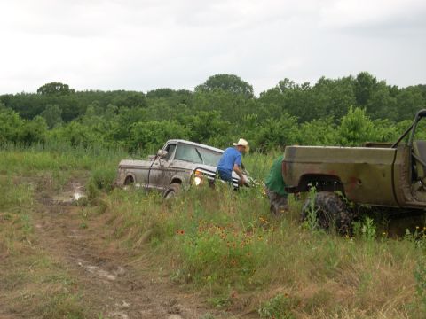 1992 Ford Bronco - Two trucks are stuck in the mud, with people attempting to get them out.