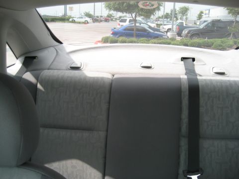 1986 Ford Bronco - View from the back seat of a car shows a parking lot with multiple vehicles outside.