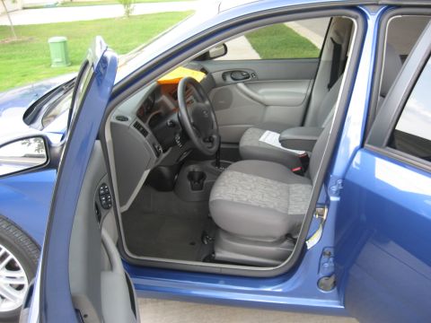 1986 Ford Bronco - Interior view of a blue car, highlighting the seats and dashboard with doors ajar.