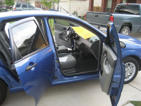 1986 Ford Bronco - Interior view of a blue sedan with front and rear doors open, showing the seats and dashboard.