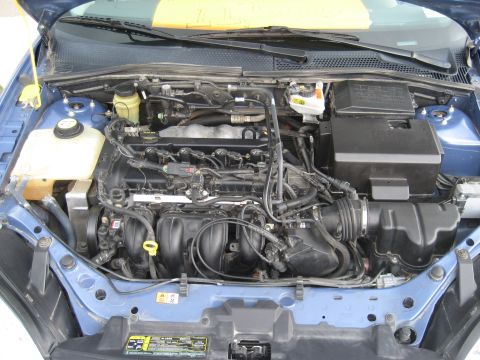 1986 Ford Bronco - The engine bay of a blue vehicle is shown, with various mechanical parts and wiring visible.