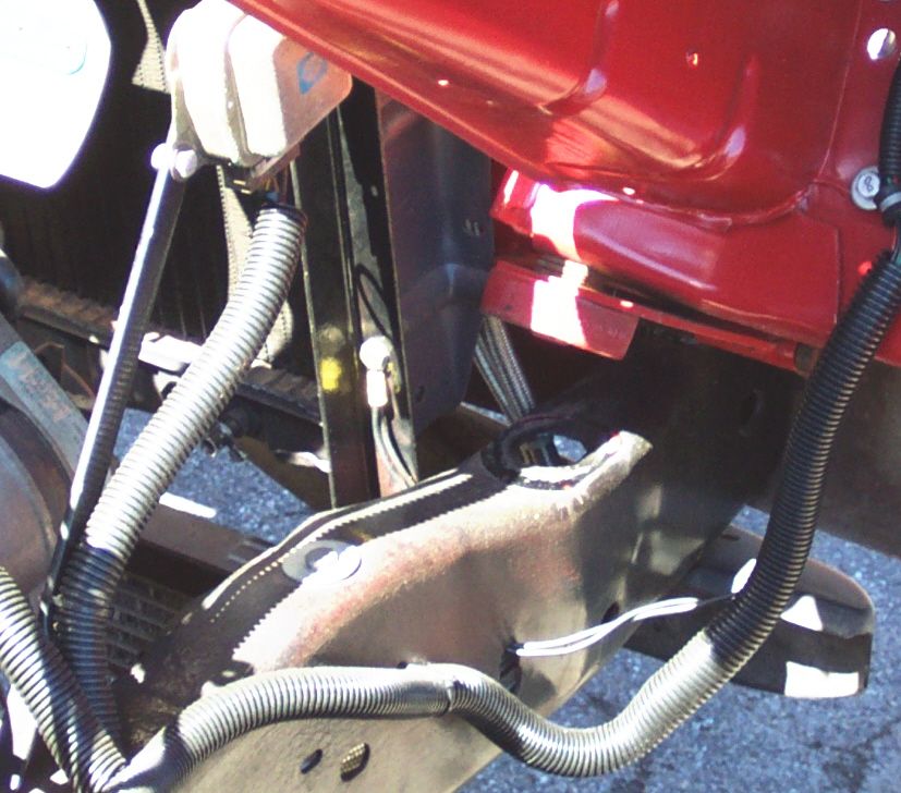 Close-up of vehicle chassis with red body panel and black wiring conduits