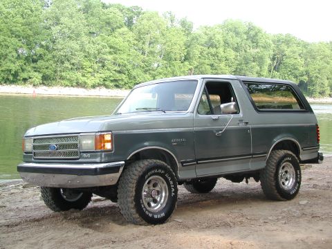 1989 Ford Bronco - This 1989 Ford Bronco is parked on a dirt bank next to a lake or river.
