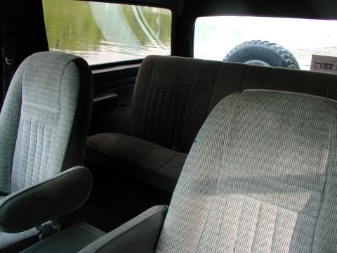 1989 Ford Bronco - The interior of a Ford Bronco shows fabric seats and a spare tire mounted in the back.