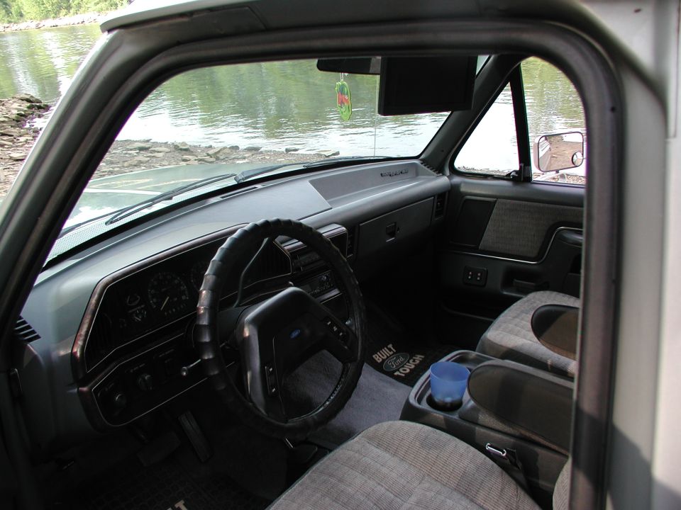1989 Ford Bronco interior showing dashboard, steering wheel, seats, and cup holder