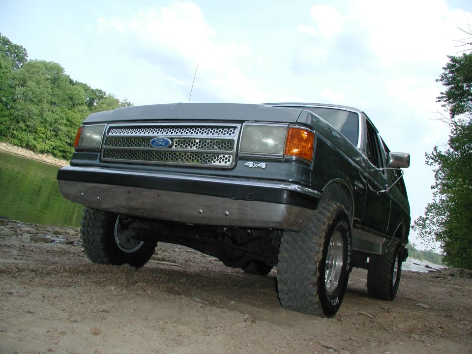 1989 Ford Bronco 4x4 parked on dirt near water, front 3/4 view